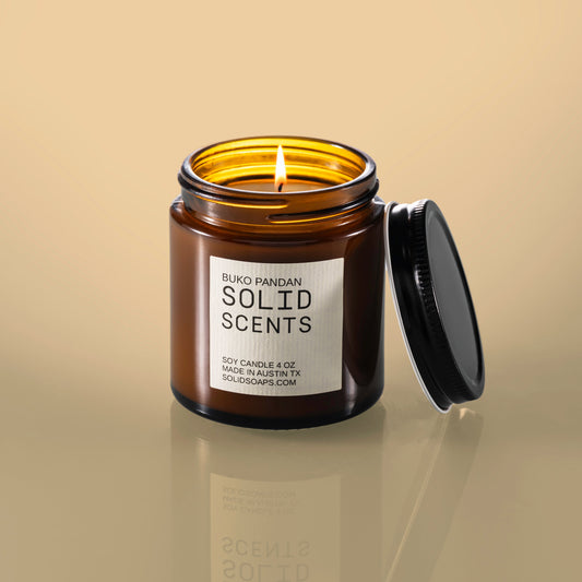 Solid Scents candle jar with a lit candle on a beige background
