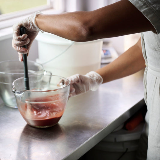 Emlyn mixing soap ingredients in a bowl with gloves