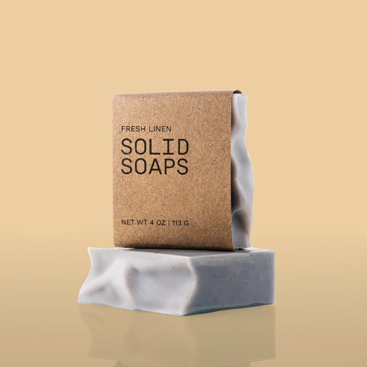Solid Soaps bar with packaging labeled 'Fresh Linen' on a reflective surface with a beige background